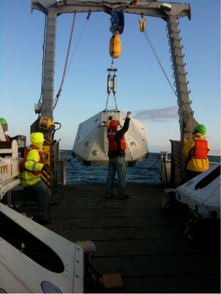Figure 3. An LDEO-TRM OBS being deployed aboard the R/V Wecoma in July 2011.::The white octagonal frame is designed to sink a few inches into the sediment and shield the seismometer from current noise and trawl fishing.